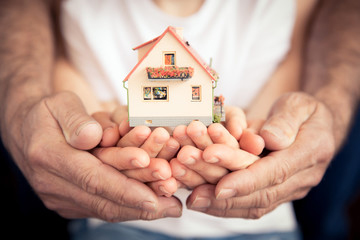 two people holding a miniature house